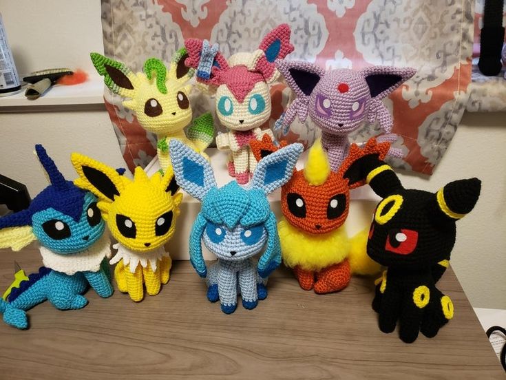 a group of knitted pokemon dolls sitting on top of a wooden table