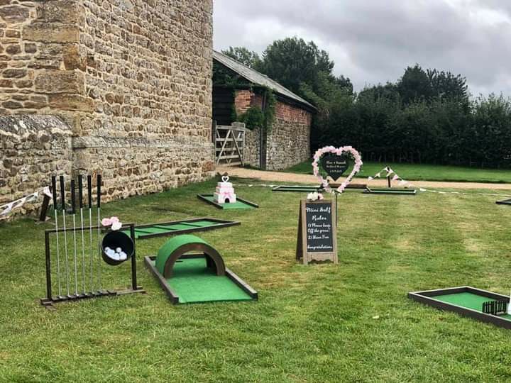 miniature golf course set up in front of an old brick building with chalkboard signs