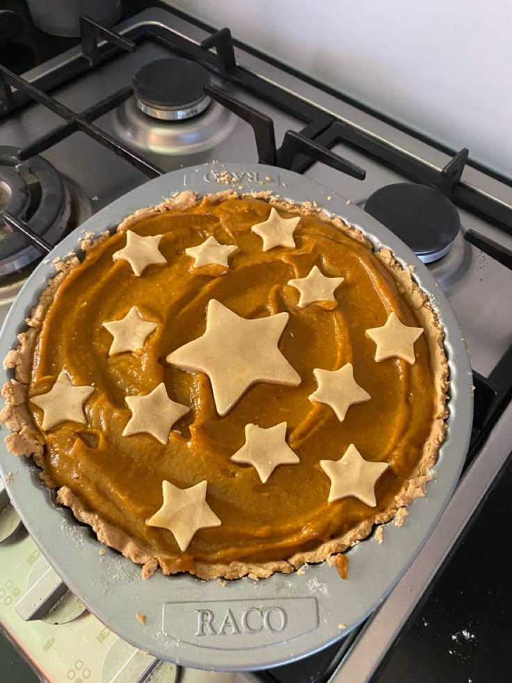 a pie sitting on top of a metal pan covered in star shaped toppings next to an oven