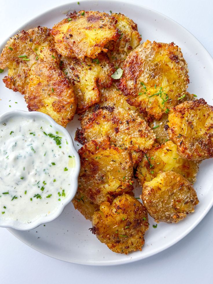 some fried food on a white plate with ranch dressing