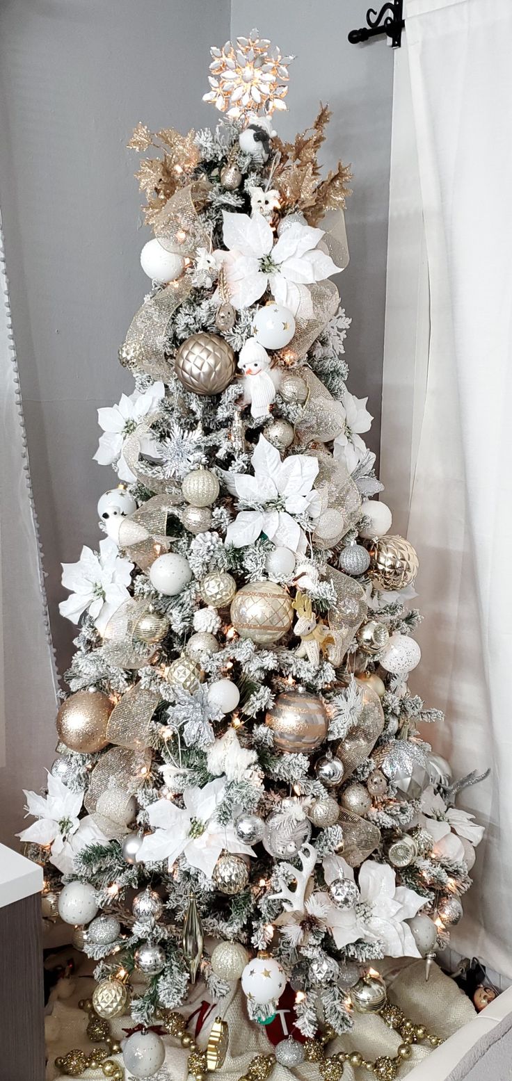 a white christmas tree with gold and silver ornaments