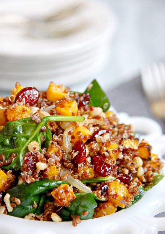 a white bowl filled with spinach and cranberry salad on top of a table