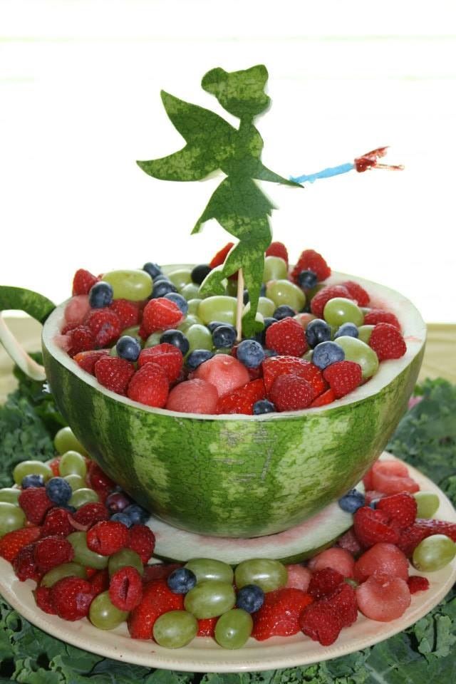 a watermelon bowl filled with berries, grapes and strawberries in the shape of a fairy