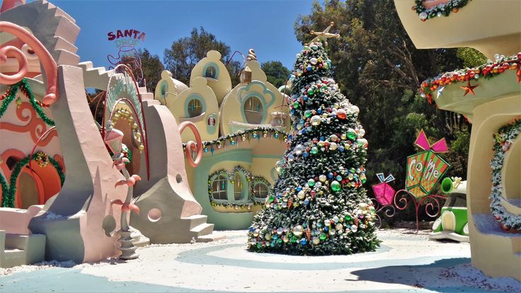 a christmas tree in the middle of a snow - covered area with buildings and trees