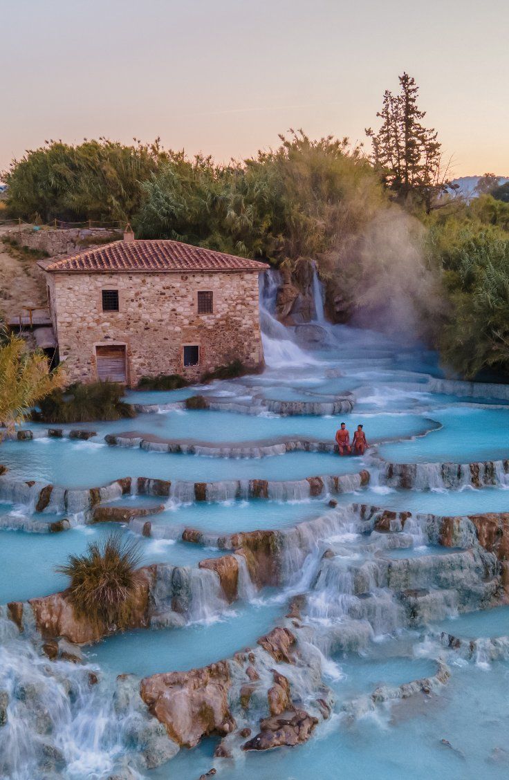 two people are standing in the middle of a blue pool with water running down it