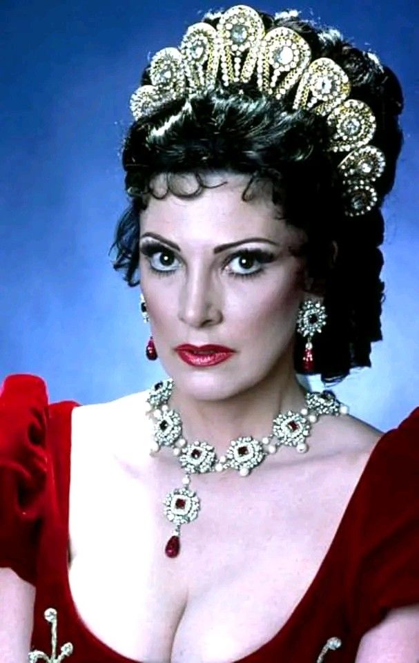 an old photo of a woman in a red dress and tiara with pearls on her head