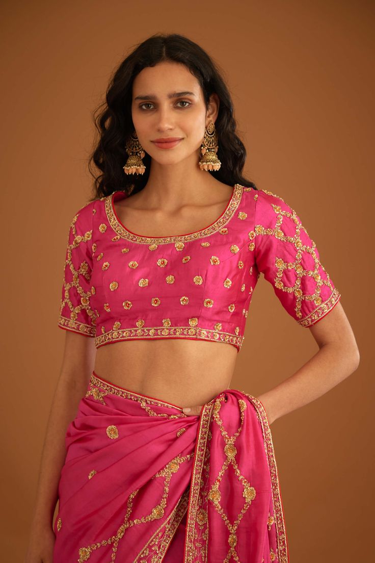 Editor's Note A fuschia pink zardozi embroidered dupion silk sari and blouse would be a stunning and bold choice for a formal occasion. The rich and luxurious fabric of the dupion silk would drape beautifully, while the intricate zardozi embroidery would add texture and depth to the overall look. Color: Pink Fabric: Dupion silk Embroidery details: Zardozi embroidery Components: Sari & blouse Sari length: 6 meters, sari width: 46" inches Occasion: Festive and Wedding Guest Disclaimer: Product col Pink Raw Silk Pre-draped Saree With Resham Embroidery, Pink Art Silk Pre-draped Saree With Intricate Embroidery, Pink Anarkali Style Silk Pre-draped Saree, Festive Pink Pre-draped Saree With Dori Work, Pink Embroidered Fitted Pre-draped Saree, Festive Pink Silk Pre-draped Saree, Designer Pink Pre-draped Saree With Zari Work, Pink Silk Pre-draped Saree In Traditional Style, Traditional Pink Silk Pre-draped Saree