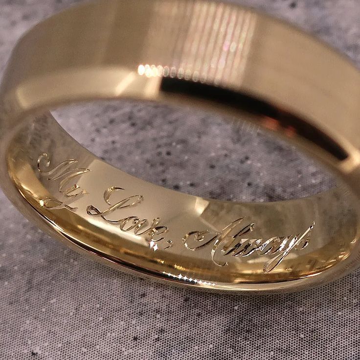 a gold wedding ring with the words love you written on it