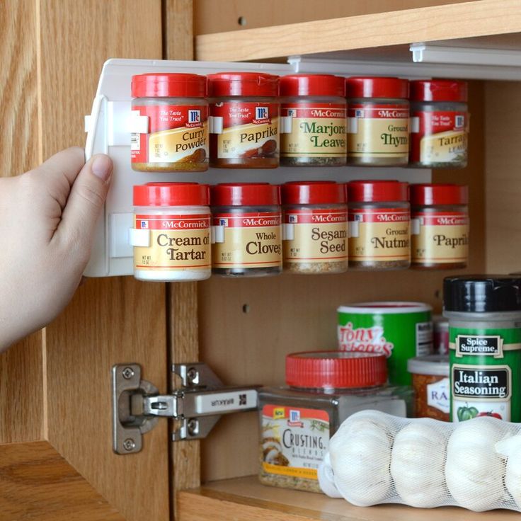 someone is picking up canned food from the pantry shelf in front of their kitchen cabinets