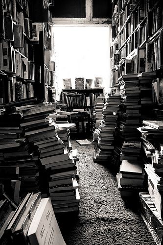 a room filled with lots of books next to a doorway covered in stacks of books