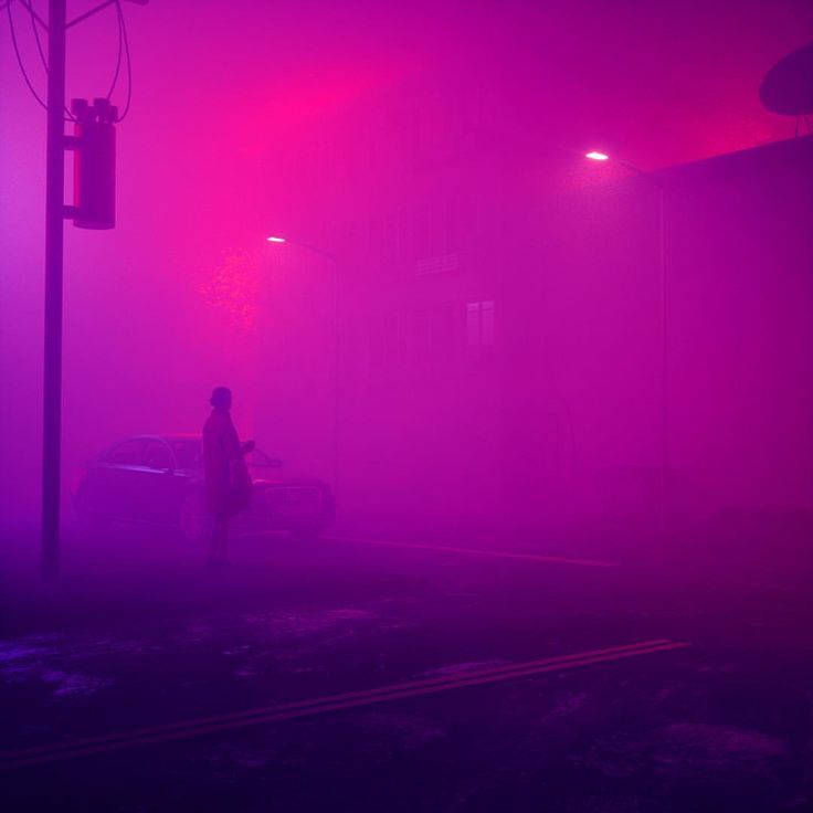 a person standing in front of a car on a foggy street at night time