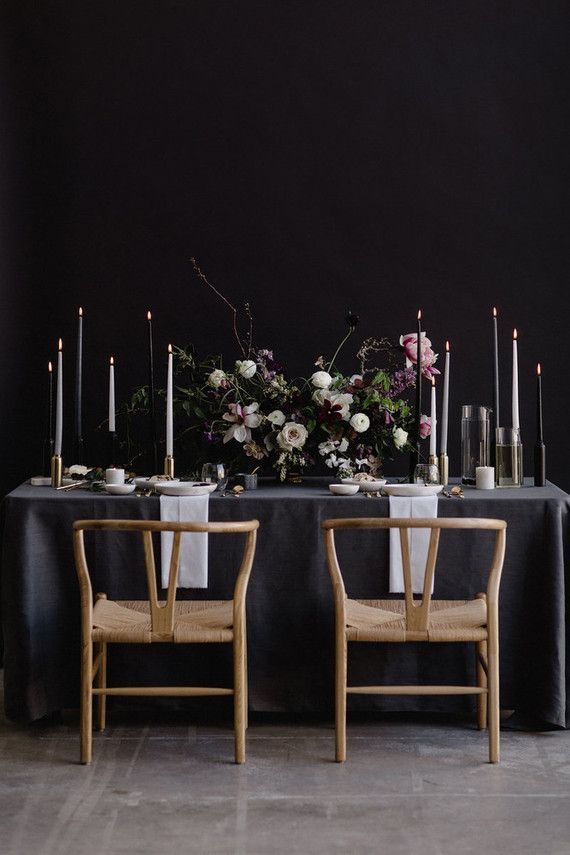 two wooden chairs sitting next to a table with flowers and candles