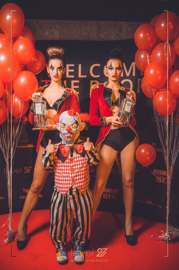 two women standing next to each other on a red carpet with balloons in the background