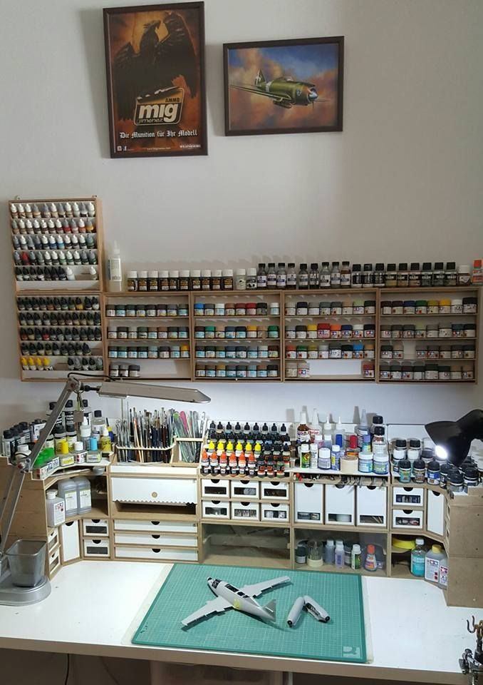 a workbench with lots of crafting supplies on the table and two framed pictures above it