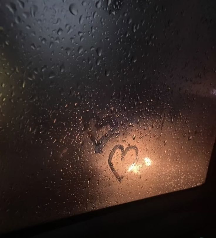 rain drops on the windshield of a car with a heart drawn on it's side