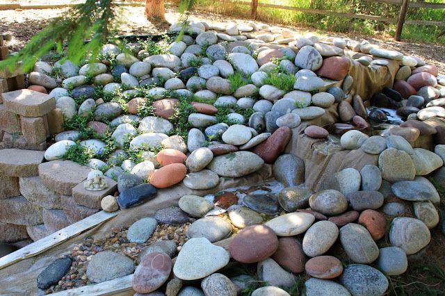 a pile of rocks sitting in the middle of a yard next to a fence and trees