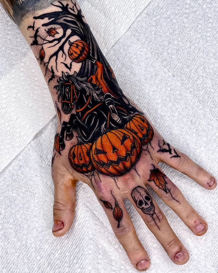 a person's hand with tattoos on it and an orange pumpkin in the middle