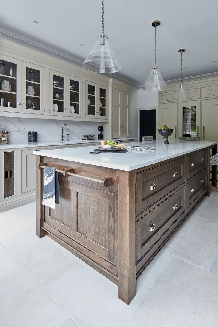 a large kitchen with an island in the middle and two lights hanging from the ceiling