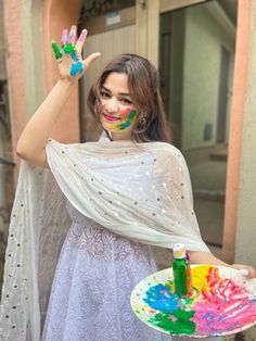 a woman holding a plate with paint on it and her hands painted in different colors