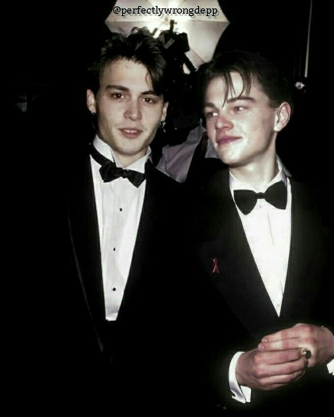 two young men in tuxedos standing next to each other at an awards event