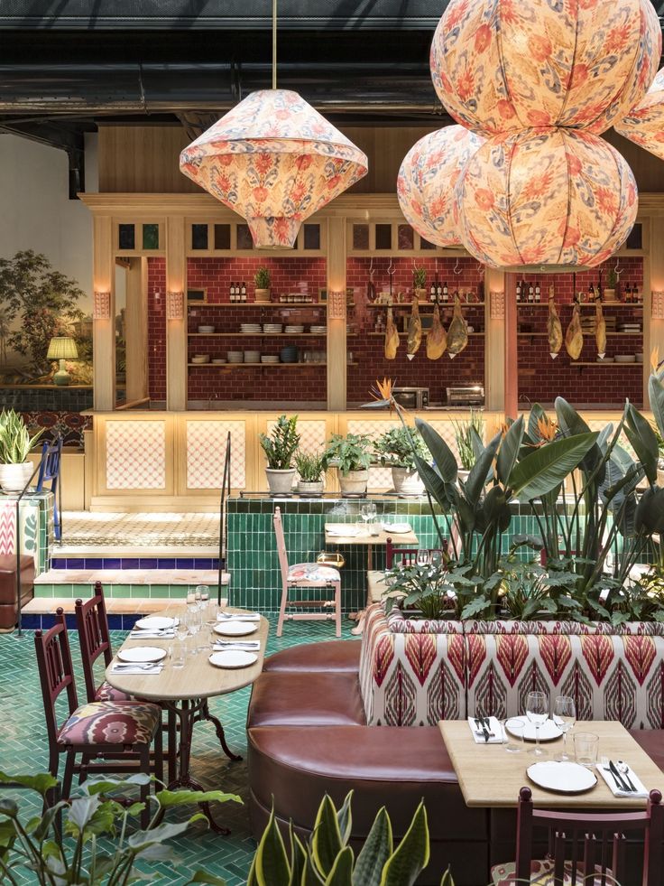 the interior of a restaurant with tables, chairs and umbrellas hanging from the ceiling