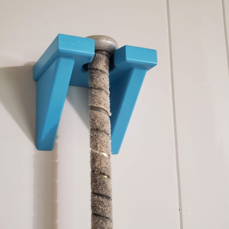 a cat scratching post with two blue posts on it's back and one pole attached to the wall