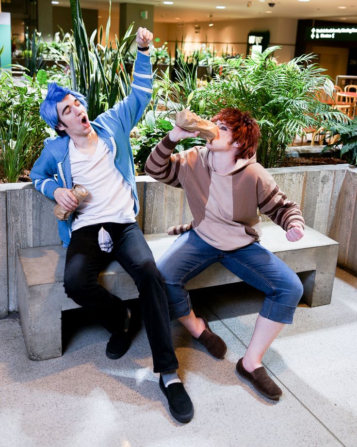 two people sitting on a bench in front of plants