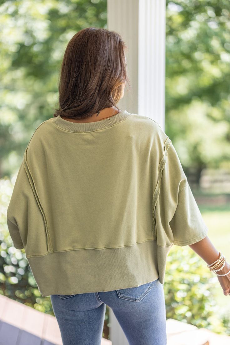 Mineral washed olive green french terry knit pullover top with hi-low bottom hem Sass up your casual attire with our Sunset Ready Washed Olive Top! This fun, comfy top features french terry knit fabric, wide 3/4 length sleeves, and a split hi-low bottom hem. Perfect for adding a quirky twist to any casual day out! Relaxed fit; semi-cropped Model is 5'5" wearing a small Fabric contains stretch Ribbed distressed crew neckline Wide 3/4 length sleeves with drop shoulder Front side slits and distress Trendy Soft-washed French Terry Tops, Oversized Olive Top For Fall, French Terry Tops For Everyday Spring Wear, Oversized French Terry Top For Spring, Oversized Khaki Sweatshirt For Spring, Oversized French Terry Tops For Layering, Oversized Relaxed French Terry Top, Casual French Terry Tops For Layering, Oversized Olive Cotton Top