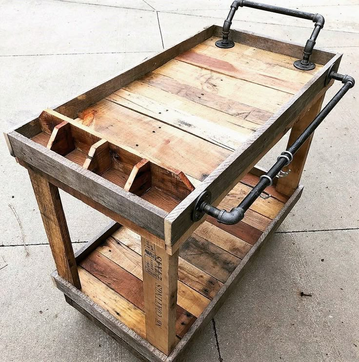 a wooden cart with metal handles on the side and two bottles in it, sitting on concrete