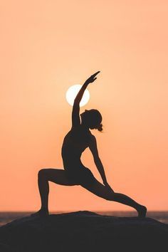 a woman doing yoga in front of the sun