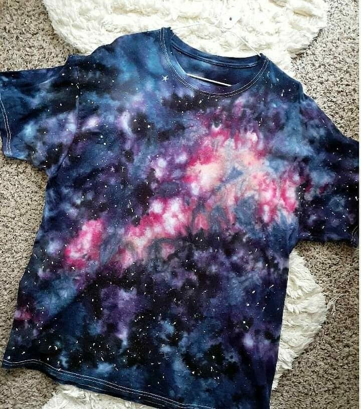 a t - shirt that is laying on the ground with space in it and stars all over it