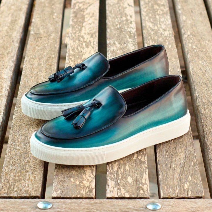 a pair of blue shoes sitting on top of a wooden bench with tassels