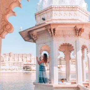 a woman standing in front of a white gazebo on the side of a body of water