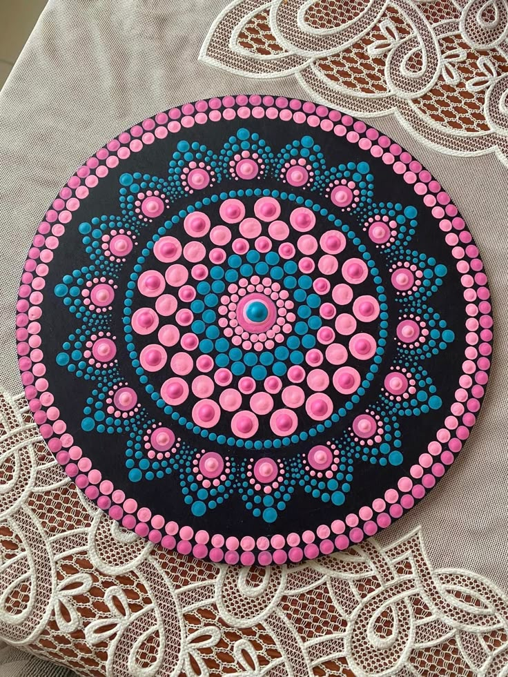 a circular design painted on top of a white table cloth with pink and blue dots