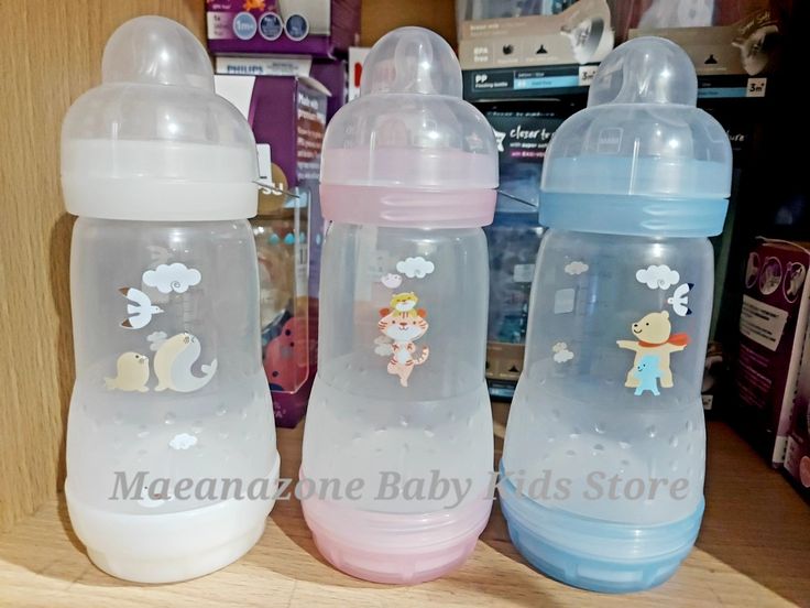 three baby bottles sitting on top of a wooden table next to each other in front of a store shelf