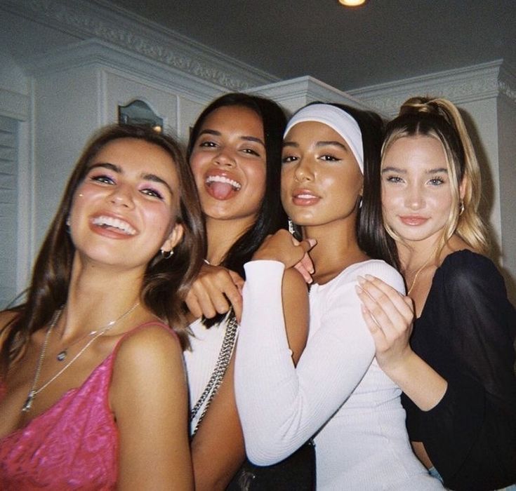 four young women posing for the camera with one holding her arm around another woman's neck