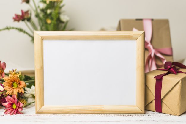 an empty wooden frame next to flowers and presents