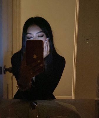 a woman looking at her cell phone while sitting in front of a sink with the light on