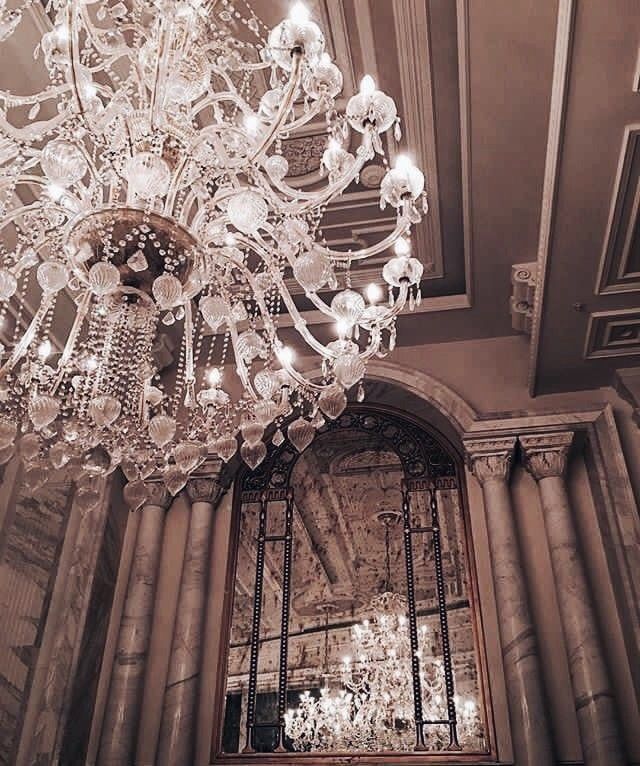 an ornate chandelier hangs from the ceiling in a room with columns and windows