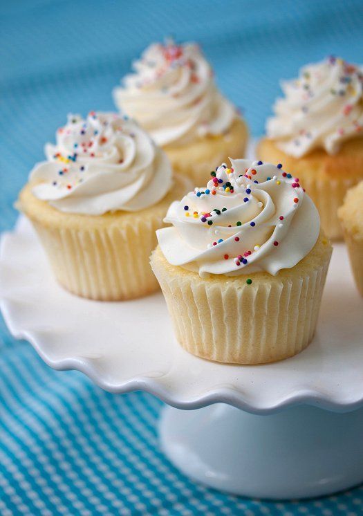 small cupcakes with white frosting and sprinkles on a plate