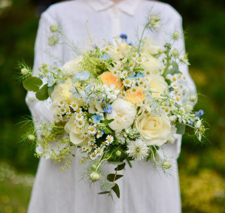 a woman holding a bouquet of white and yellow flowers