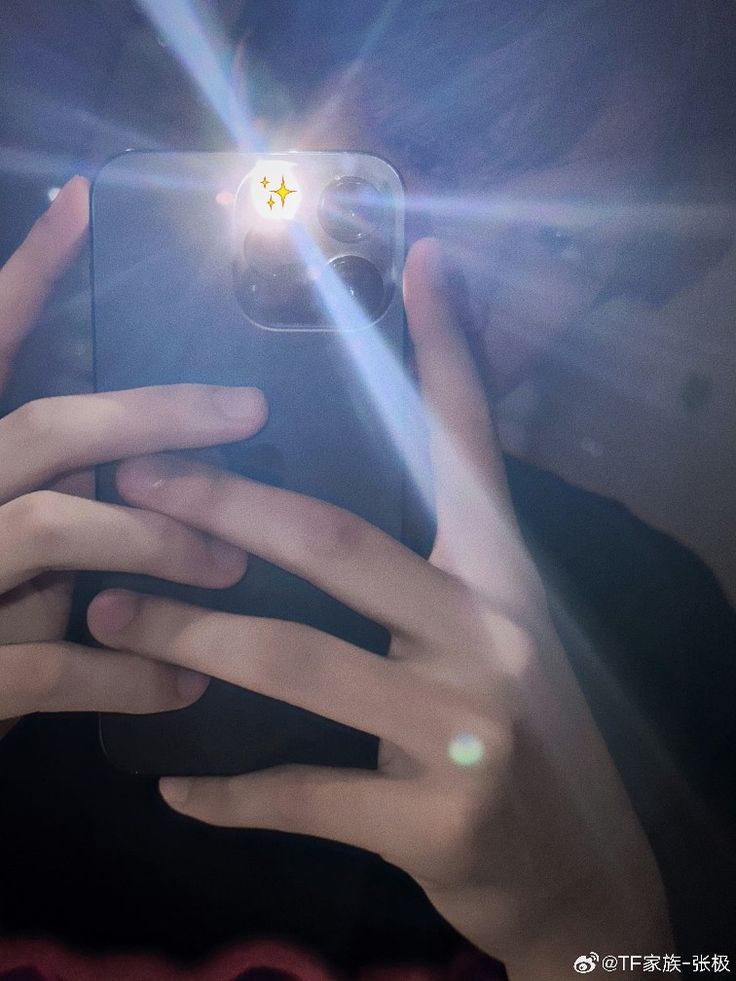 someone holding up their phone to take a photo with the light shining on them,