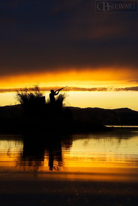 the silhouette of a person standing on top of a small island in the water at sunset