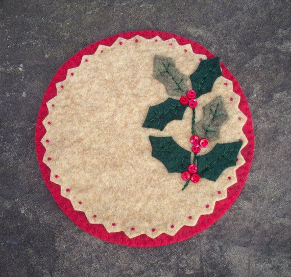 a red and white table mat with holly leaves on it, sitting on the ground