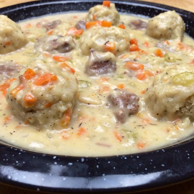 a black bowl filled with meatballs and gravy