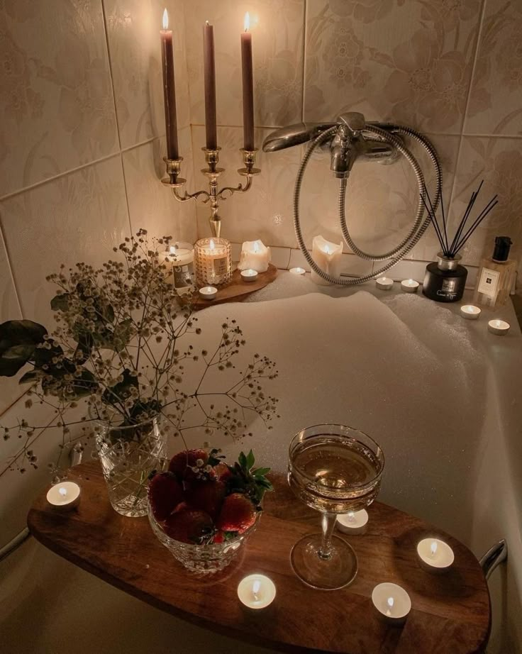 candles are lit in the bathroom next to a bathtub with strawberries on it