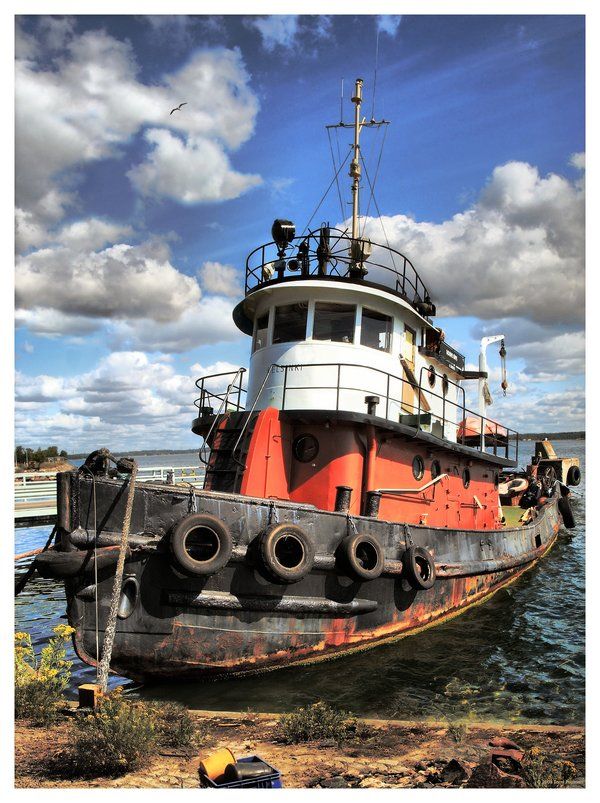 an old rusted tug boat sitting in the water with people on it's deck