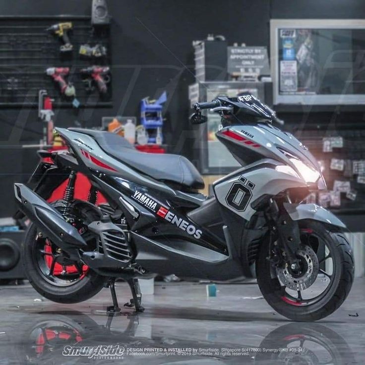 a motorcycle is parked in a garage with other tools on the wall and behind it