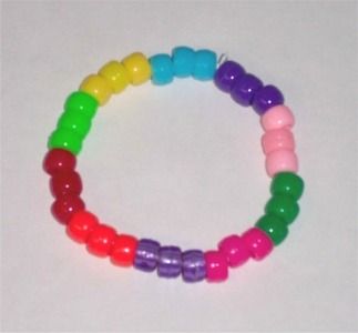 a bracelet made out of plastic beads on a white surface with one bead in different colors