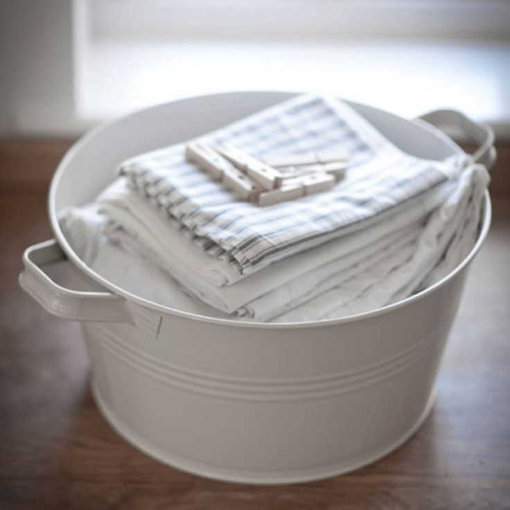 a bucket filled with white towels on top of a wooden floor